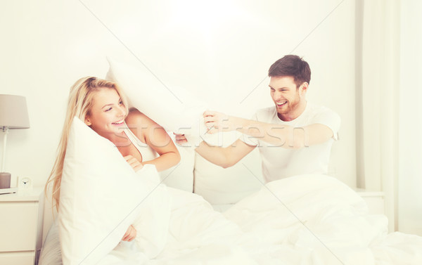 Heureux couple bataille d'oreillers lit maison personnes [[stock_photo]] © dolgachov