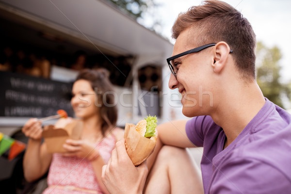 happy man eating hamburger at food truck Stock photo © dolgachov