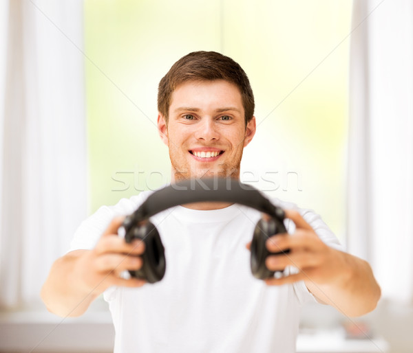 young smiling man offering headphones at home Stock photo © dolgachov