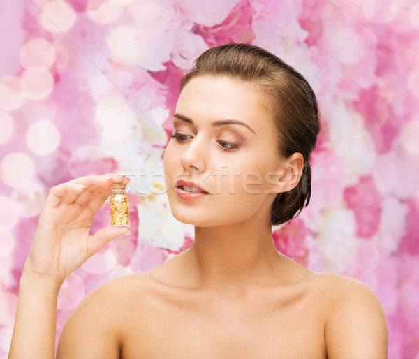 beautiful woman showing bottle with golden dust Stock photo © dolgachov