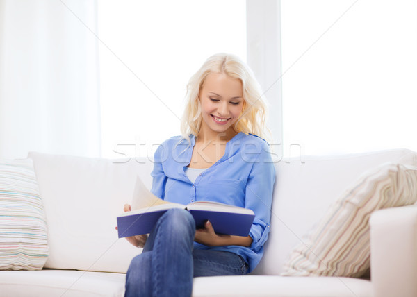 smiling woman reading book and sitting on couch Stock photo © dolgachov