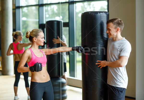 smiling woman with personal trainer boxing in gym Stock photo © dolgachov