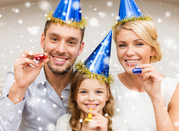 smiling family in party hats blowing favor horns Stock photo © dolgachov