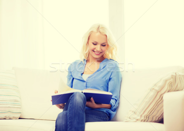 smiling woman reading book and sitting on couch Stock photo © dolgachov