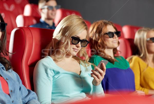 Stock photo: happy woman with smartphone in 3d movie theater