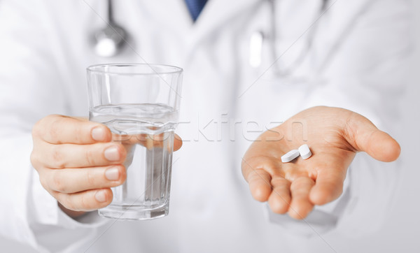 doctor hands giving white pills and glass of water Stock photo © dolgachov