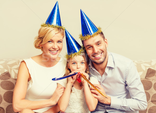 smiling family in blue hats blowing favor horns Stock photo © dolgachov