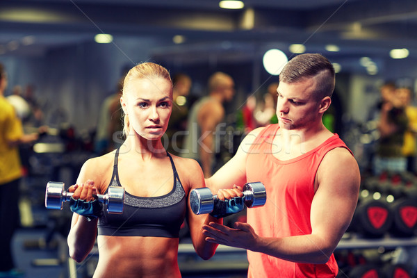 young couple with dumbbells flexing muscles in gym Stock photo © dolgachov