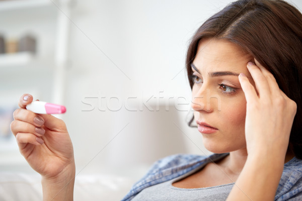 Stock photo: sad woman looking at home pregnancy test