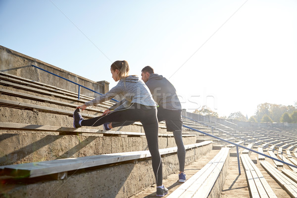 couple stretching leg on stands of stadium Stock photo © dolgachov