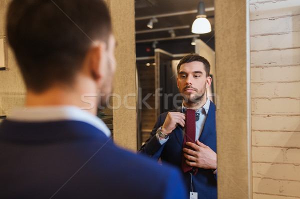 man trying tie on at mirror in clothing store Stock photo © dolgachov
