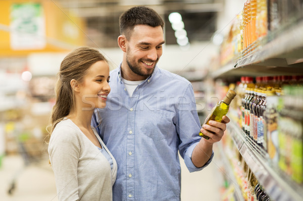 Stock photo: happy couple buying olive oil at grocery store