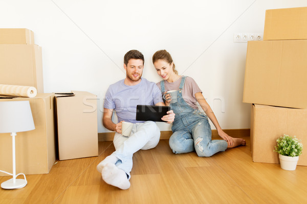 Stock photo: couple with boxes and tablet pc moving to new home