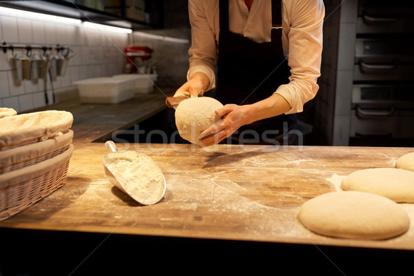 baker portioning dough with bench cutter at bakery Stock photo © dolgachov