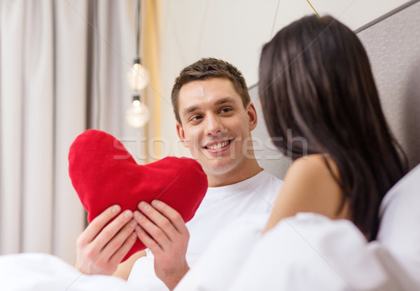 smiling couple in bed with red heart shape pillow Stock photo © dolgachov