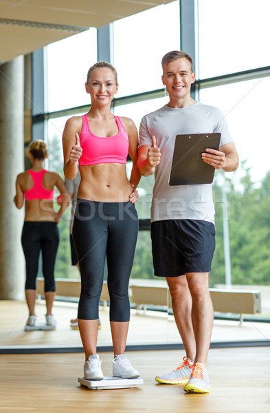 smiling man and woman with scales in gym Stock photo © dolgachov