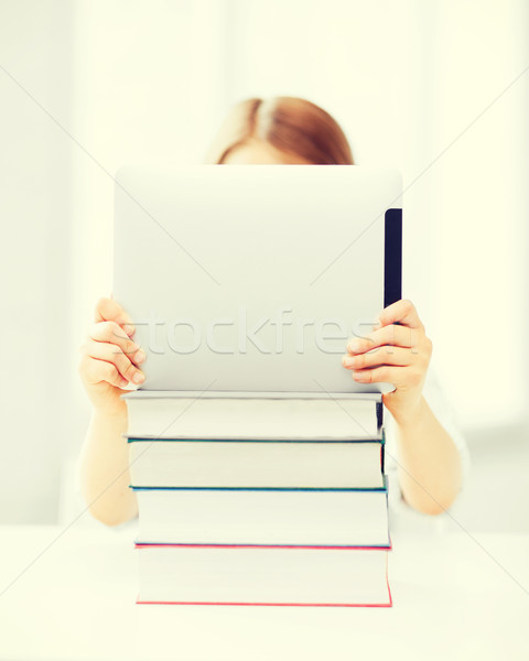 Stock photo: girl hiding behind tablet pc and books at school