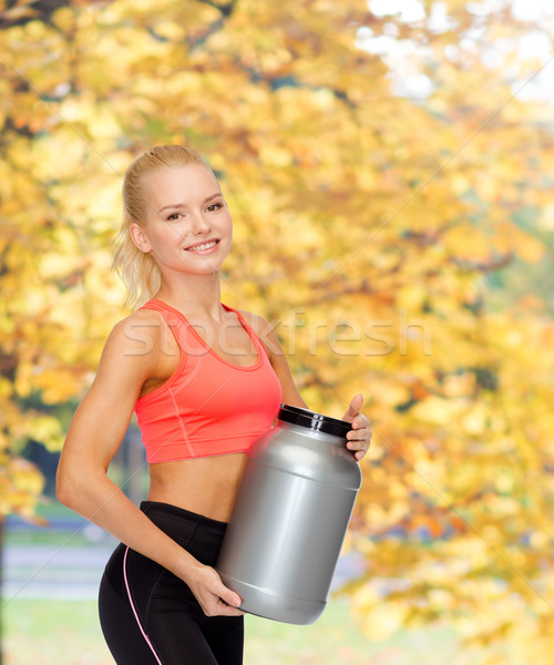 smiling sporty woman with jar of protein Stock photo © dolgachov