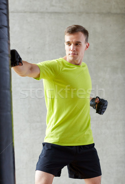 young man in gloves boxing with punching bag Stock photo © dolgachov