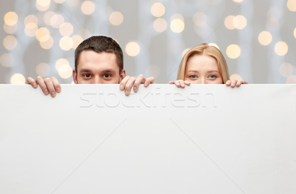 happy couple hiding behind big white blank board Stock photo © dolgachov