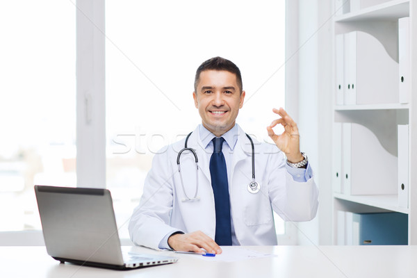 smiling doctor with laptop showing ok in office Stock photo © dolgachov
