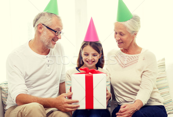 smiling family in party hats with gift box at home Stock photo © dolgachov