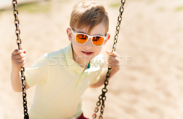 happy little boy swinging on swing at playground Stock photo © dolgachov