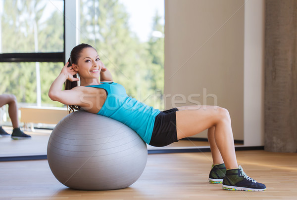 smiling woman with fit ball flexing muscles in gym Stock photo © dolgachov
