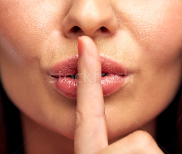 close up of young woman holding finger on lips Stock photo © dolgachov