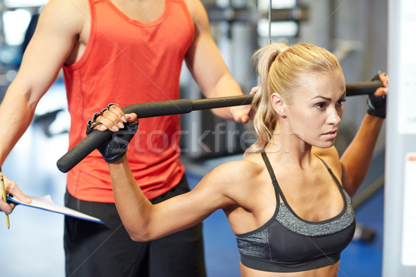 Stock photo: man and woman flexing muscles on gym machine