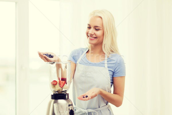 Stock photo: smiling woman with blender preparing shake at home