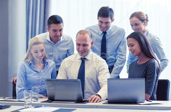 Stock photo: smiling businesspeople with laptops in office
