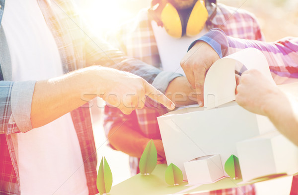 Stock photo: close up of builders with paper house model