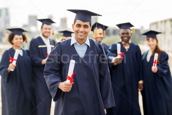 Stock photo: happy students in mortar boards with diplomas