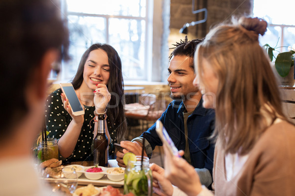 Stock photo: friends with smartphones and food at bar or cafe
