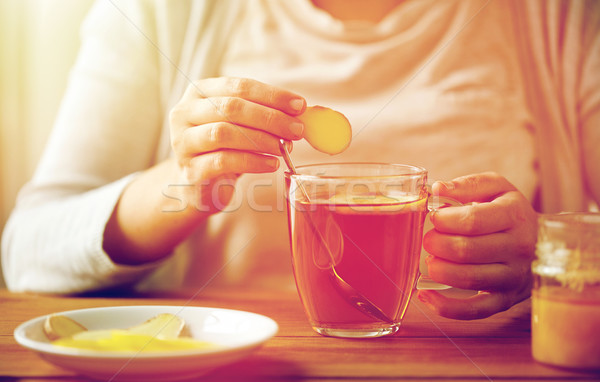 close up of woman adding ginger to tea with lemon Stock photo © dolgachov