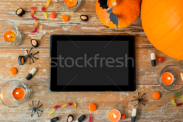 halloween pumpkins, candies, candles and tablet pc Stock photo © dolgachov