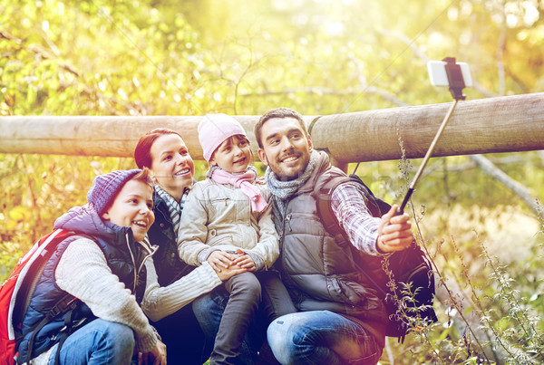 Stock photo: happy family with smartphone selfie stick in woods