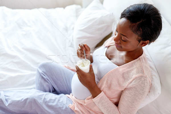 Femeie gravida mananca iaurt pat sarcină oameni Imagine de stoc © dolgachov