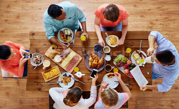 Oameni smartphone-uri mananca alimente tabel mic dejun Imagine de stoc © dolgachov