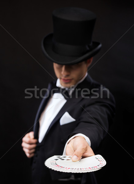 magician in hat showing trick with playing cards Stock photo © dolgachov