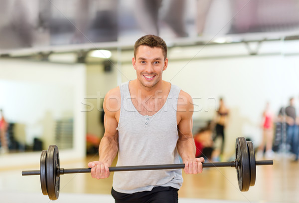 Stock photo: smiling man with barbell in gym