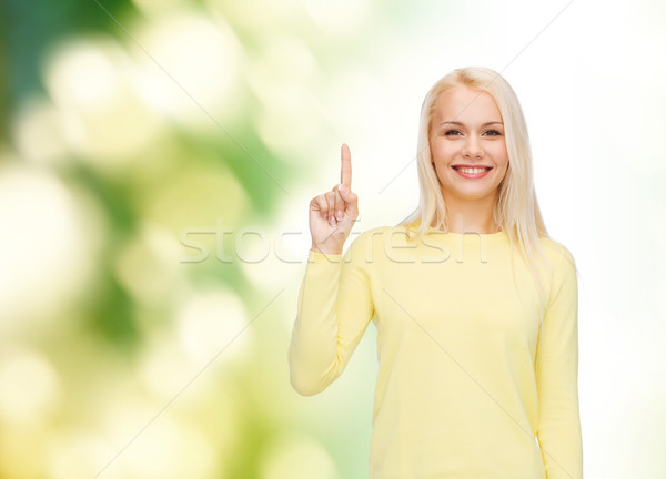 smiling woman pointing her finger up Stock photo © dolgachov