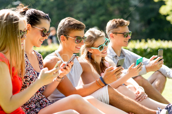 Sorridere amici smartphone seduta erba amicizia Foto d'archivio © dolgachov