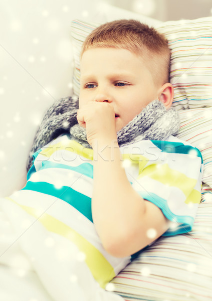 Stock photo: ill boy with scarf lying in bed and coughing