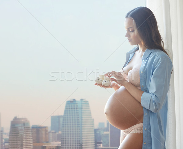 happy pregnant woman with baby booties at home Stock photo © dolgachov