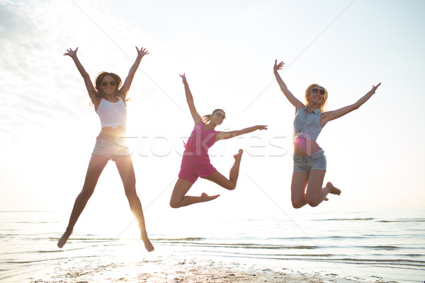 happy female friends dancing and jumping on beach Stock photo © dolgachov