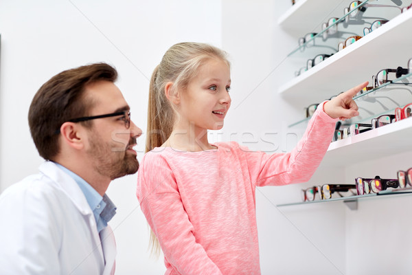 optician and girl choosing glasses at optics store Stock photo © dolgachov