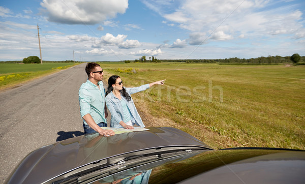 happy man and woman with road map on car hood Stock photo © dolgachov