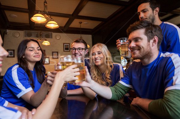 football fans clinking beer glasses at sport bar Stock photo © dolgachov